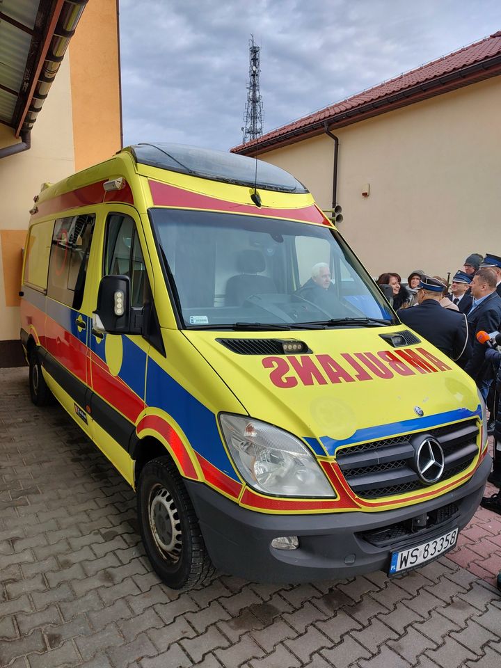 Grafika przedstawia napis Pięć nowych ambulansów dla Meditrans w Siedlcach. Tak pomagają Fundusze Europejskie. W tle widać karetki.